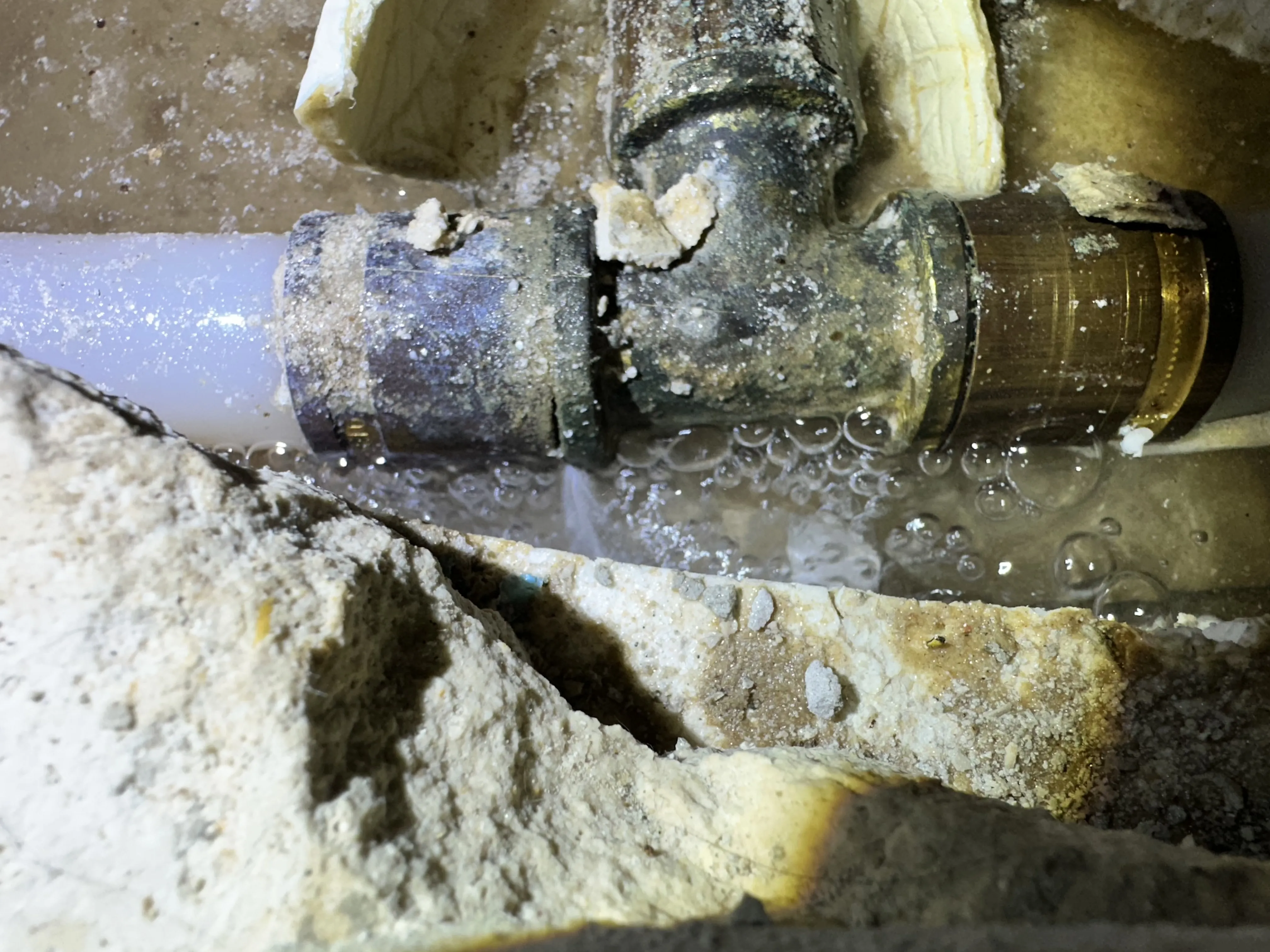 Wasser tropft aus undichte Rohrverbindung mit Blasen unter dem Metall-T-Stück.