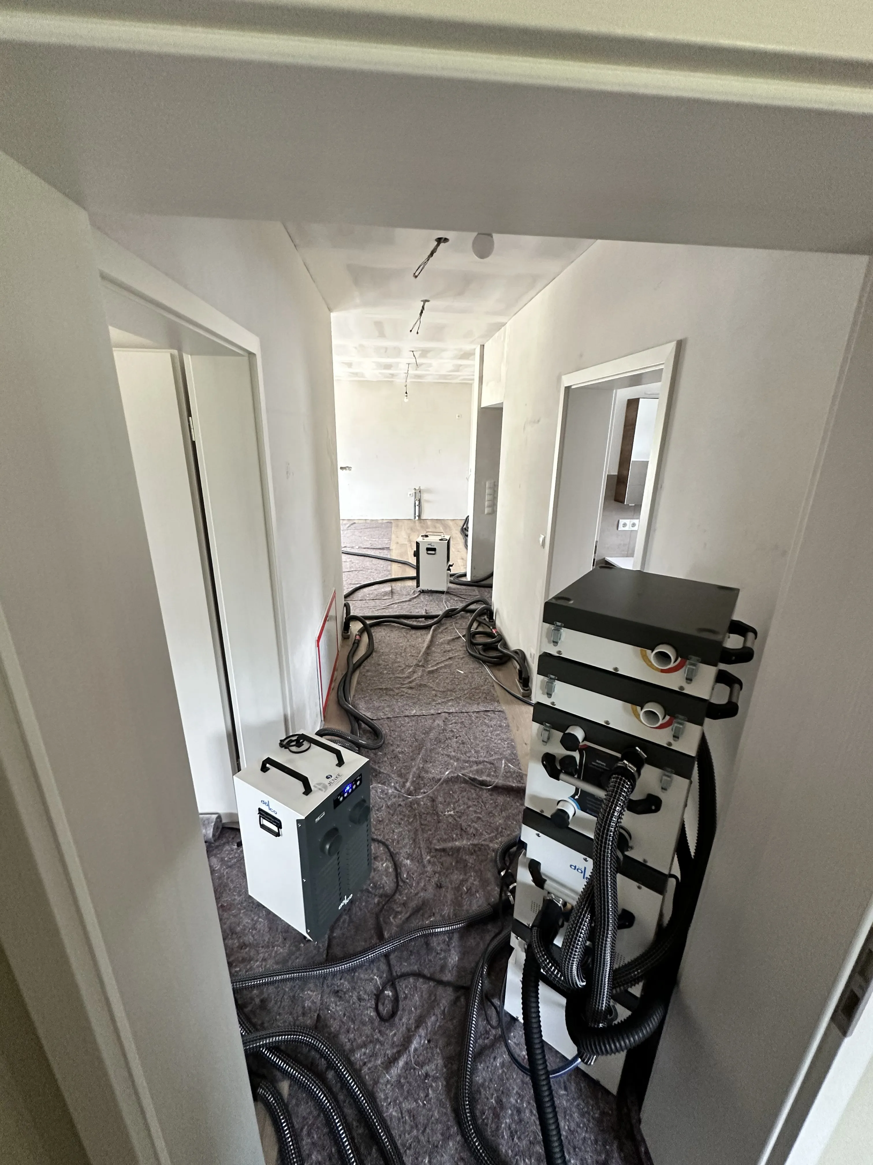 Flur mit Lüftungsgerät und Schläuchen in einer Wohnung im Umbau.
